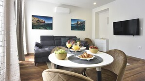 Una sala de estar moderna con un sofá, una mesa de comedor con alimentos para el desayuno y dos cuadros en la pared.