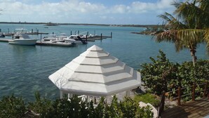 A marina with several boats docked, a white gazebo, and a palm tree. - February Point Resort Estates BB1 (George Town)