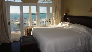 A hotel room with a large bed, a view of the marina, and a balcony with curtains. - February Point Resort Estates BB1 (George Town)