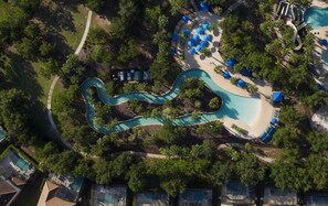 An aerial view of a resort with a winding pool, lounge areas, and dense greenery. - 10% off Fall 2026 5-Bedroom Luxury Retreat w/ Modern Updates & Premium Amenities (Davenport)