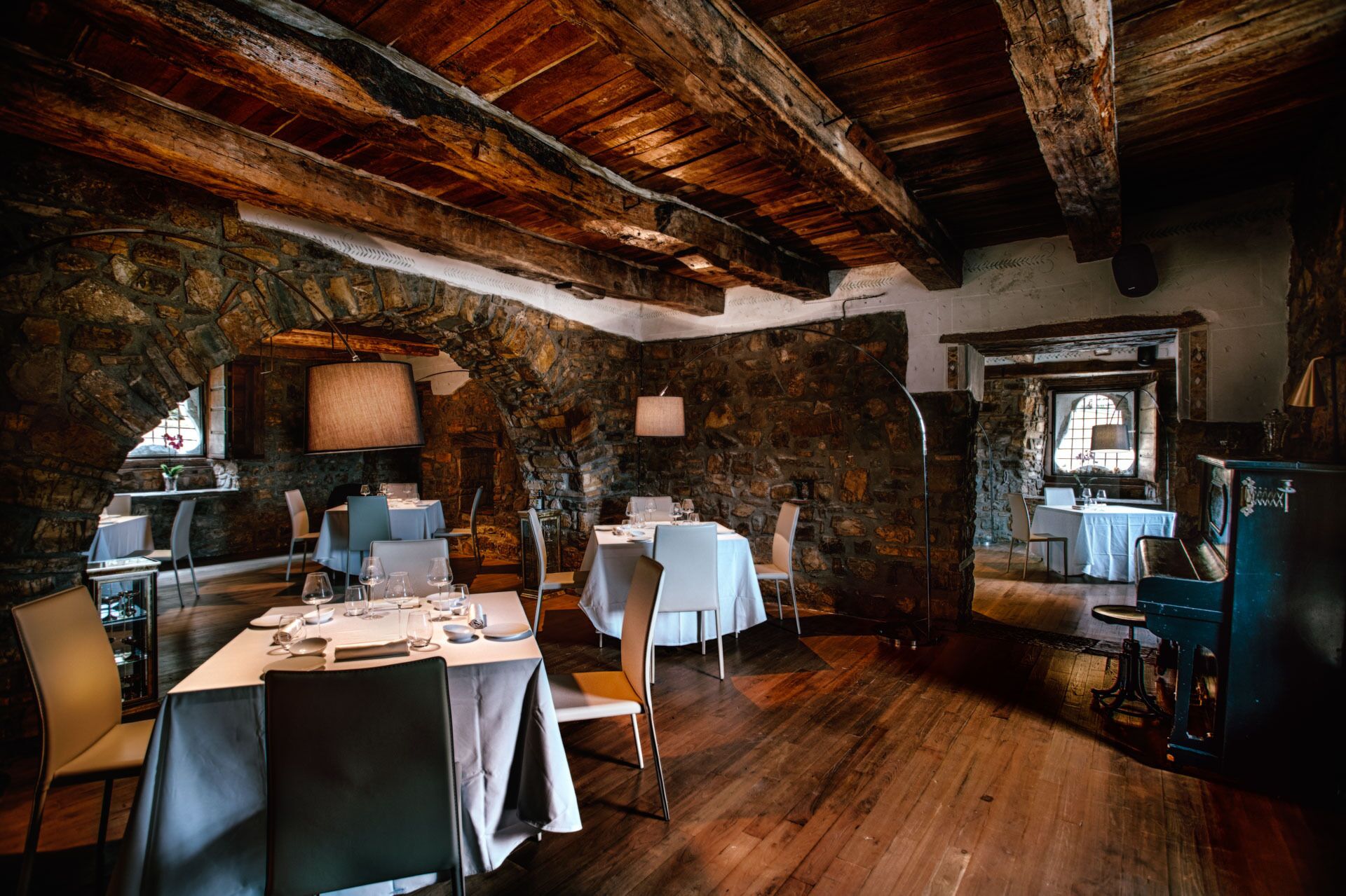 Un'accogliente sala da pranzo rustica, con pareti in pietra, travi in legno e tavoli apparecchiati.