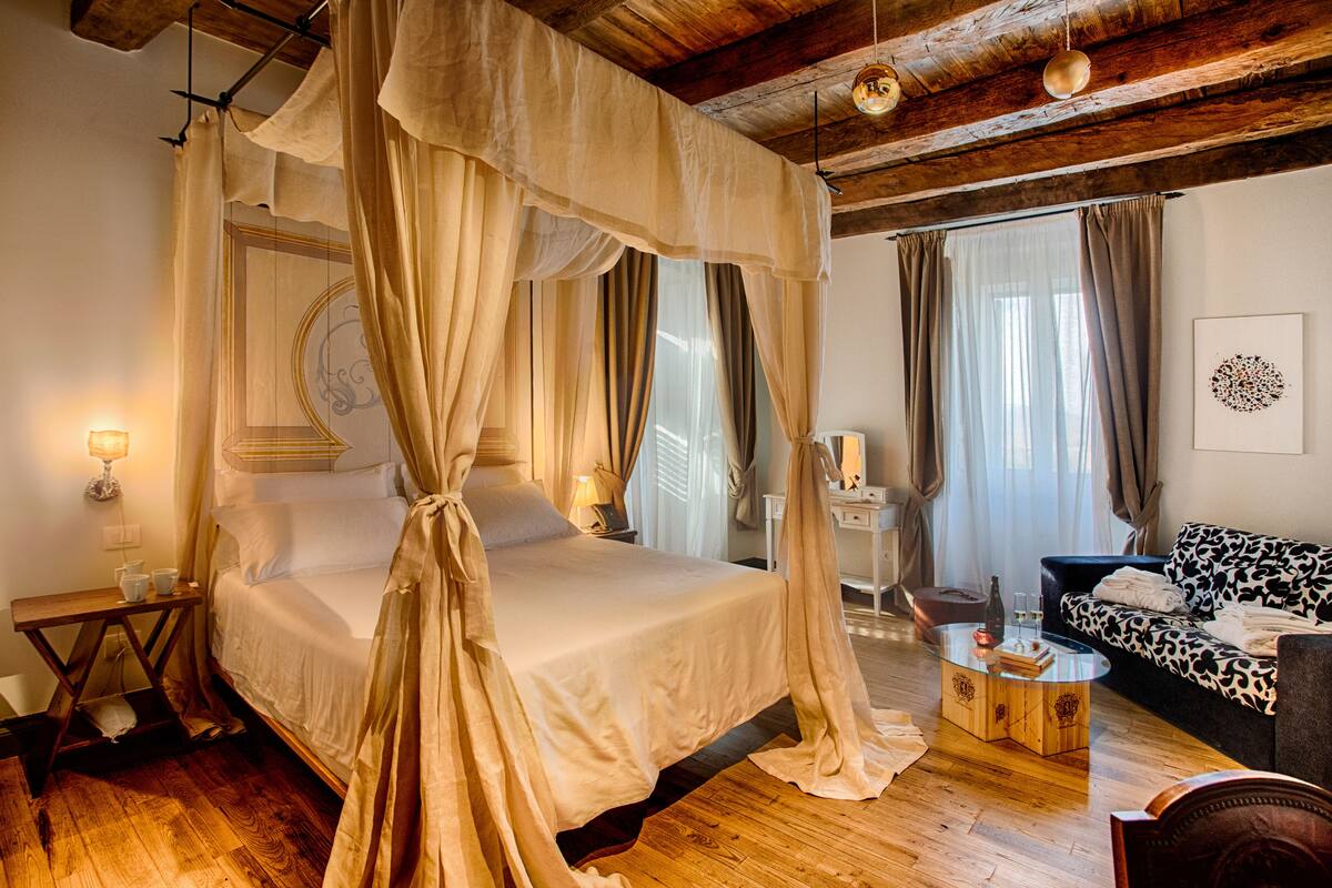 A bedroom with a four-poster bed, a sofa, and a coffee table.