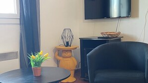 Un salón con una mesa redonda, un sofá, un televisor y una estatua decorativa de un oso.