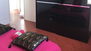 Un dormitorio con cama, un armario negro y una puerta que da a otra habitación.