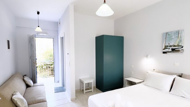 Et moderne hotelværelse med seng, sofa, et lille bord og et garderobeskab.