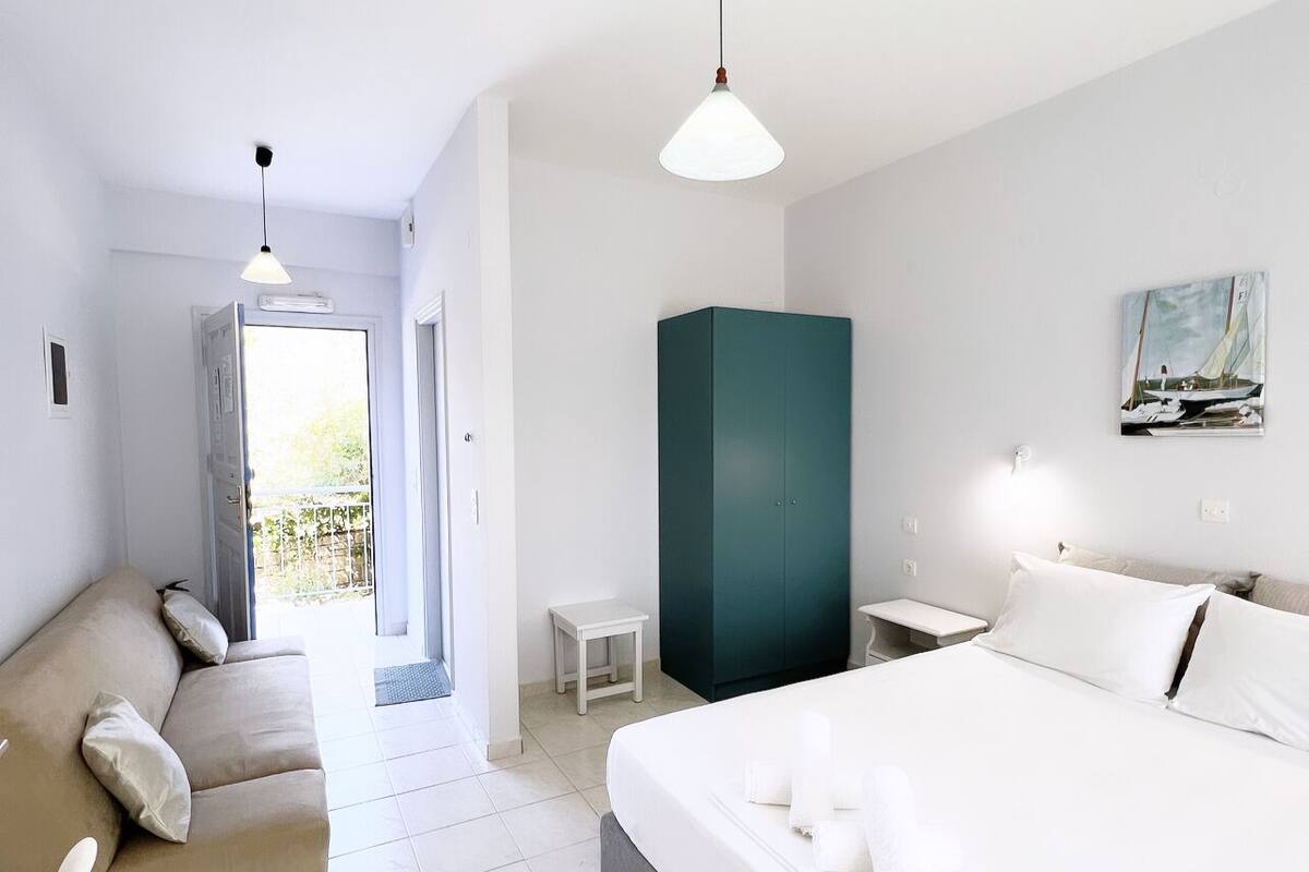 A modern hotel room with a bed, a sofa, a small table, and a wardrobe.