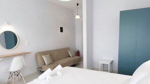 Et moderne hotelværelse med en stor seng, en sofa, et lille bord og et spejl.