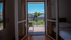 A room with a sliding glass door leading to a balcony with a view of houses and trees. - Spacious room for 8 people near the beach (Seline)