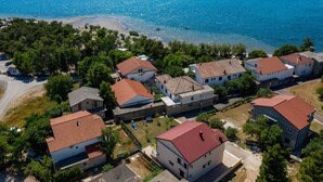 A coastal residential area with houses having red-tiled roofs, surrounded by greenery and a beach. - Spacious room for 8 people near the beach (Seline)