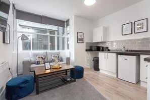 A modern kitchen with white cabinets, a black countertop, and a window overlooking the street. - Charnley House Apartment 3 (Blackpool)