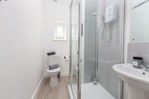Ein modernes Badezimmer mit Duschkabine aus Glas, einem weißen Waschbecken und einer Toilette.