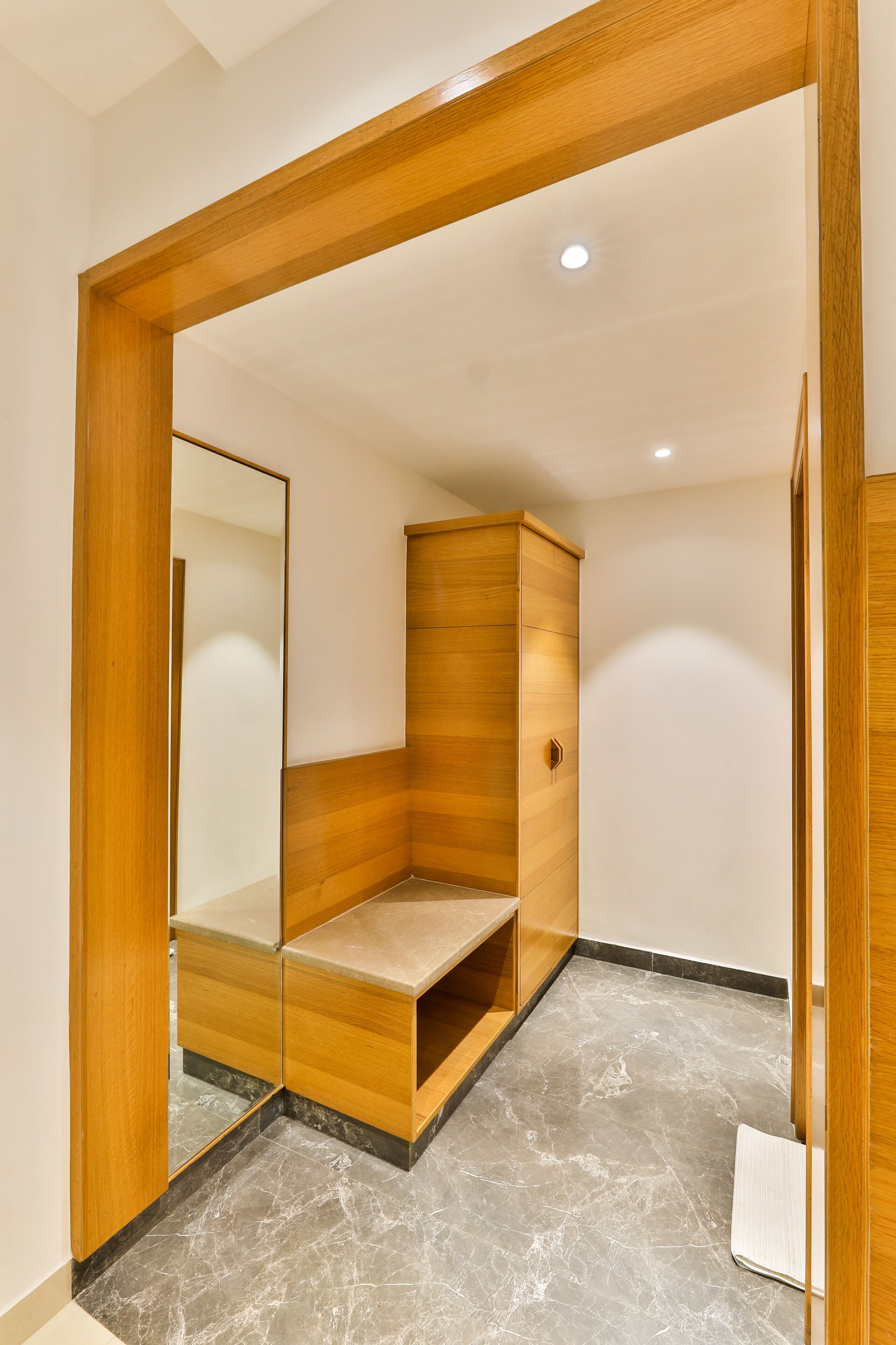 Une salle de bain moderne avec un meuble-lavabo en bois, un miroir et un sol en marbre.