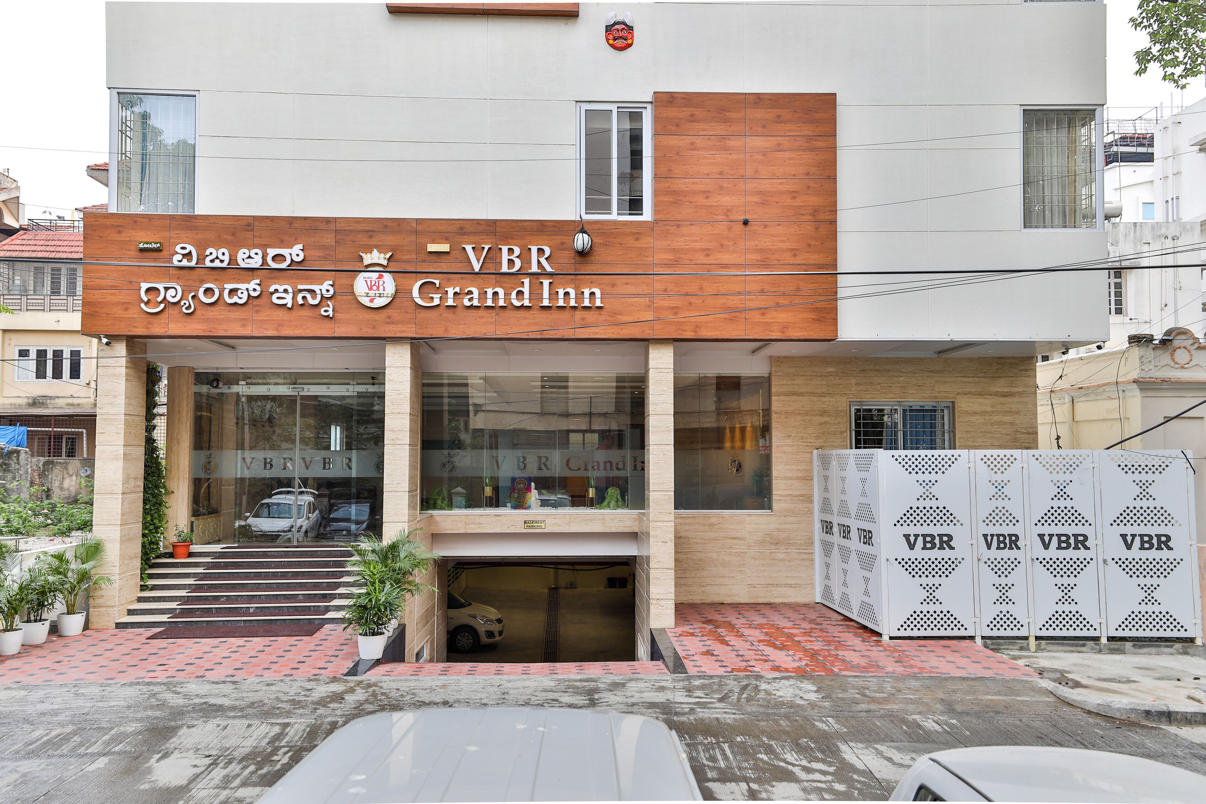 Entrada de un hotel con un letrero que dice "VBR Grand Inn" y un coche estacionado en la entrada.