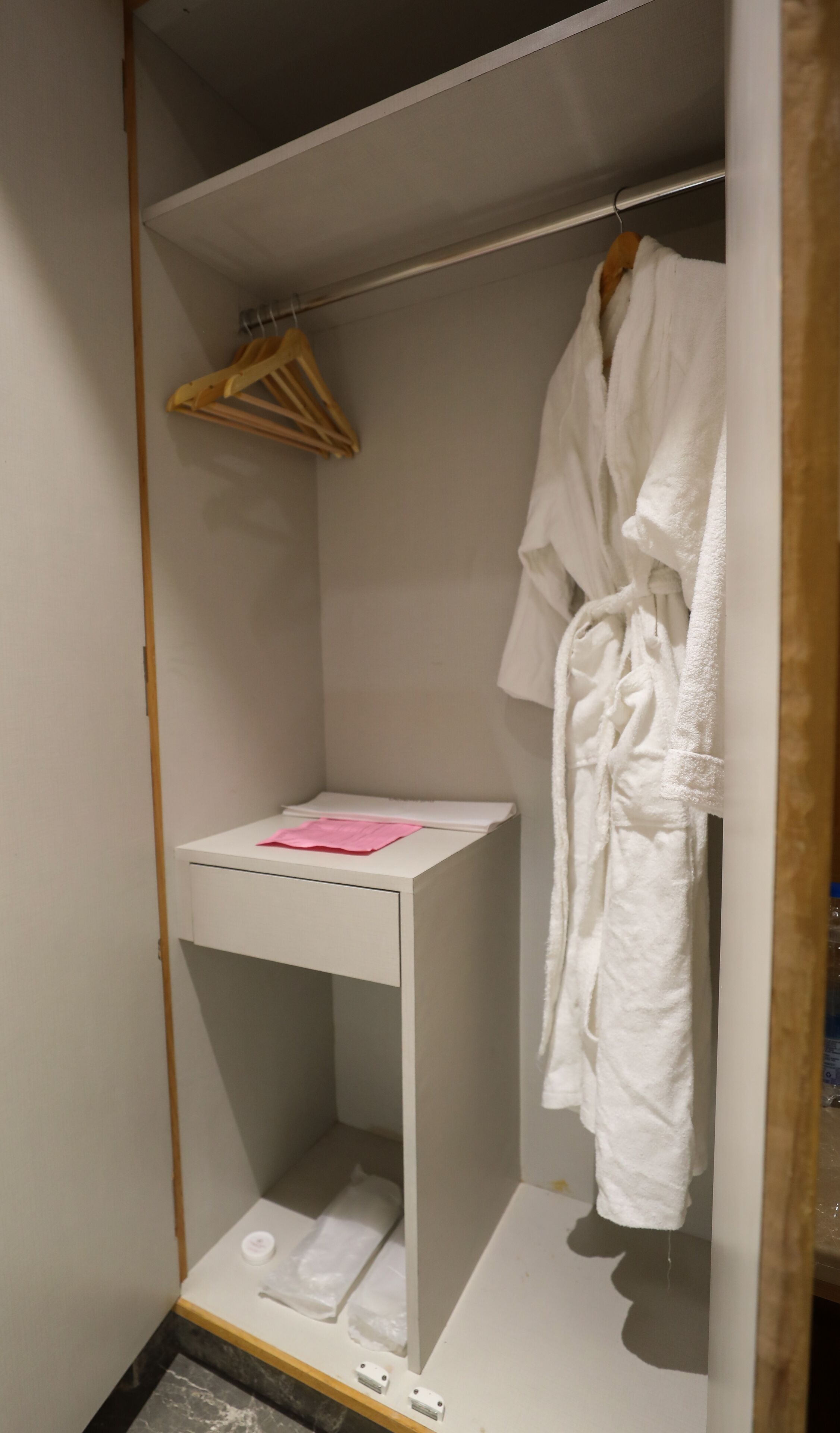A walk-in closet with a white vanity, a hanging rack, and a robe.