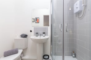 Ein modernes Badezimmer mit Toilette, Waschbecken und einer Duschkabine.