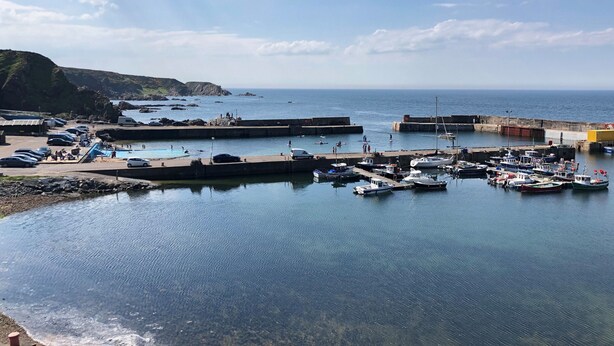 A coastal marina with boats docked, a swimming area, and a parking lot with cars. - 4 Gordon Street (Buckie)