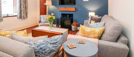A living room with a fireplace, a television mounted on the wall, and a sofa with patterned cushions.
