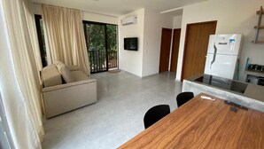 Una sala de estar moderna con un sofá, una mesa de comedor y una zona de cocina con un refrigerador.