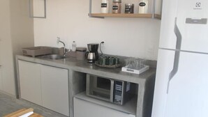 Una cocina moderna con microondas integrado, cafetera y estantes para almacenamiento.