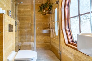 A modern bathroom with a glass-enclosed shower, a white toilet, and a window providing natural light. - B&B Singel Suites (Amsterdam)
