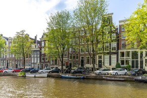 A canal with boats and parked cars along the side of a row of traditional buildings. - B&B Singel Suites (Amsterdam)