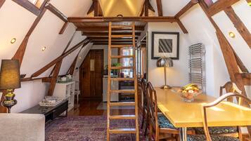 A cozy dining area with a wooden table, chairs, and a ladder leading to an upper level.