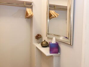 A bathroom with a mirror, towel rack, vase, and a tissue box.