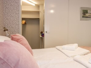 A bedroom with a bed, pillows, a closet, and a bathroom with a towel. - The Toll House (Melrose)