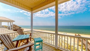 A covered outdoor area with wooden furniture, a view of the beach, and a clear sky. - Luxury 6 Bdrm Gulf Front w/Dune Walkover, Amazing Gulf Views (Gulf Shores)