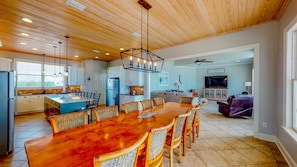 Un'ampia cucina con una grande isola, soffitto in legno e lampade moderne.