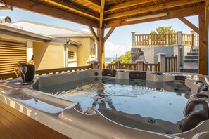 A hot tub with a wooden deck and a view of the ocean.