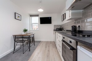 A modern kitchen with a dining area, a flat-screen TV, and a window.