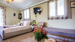 Ein Schlafzimmer mit einem Bett, einem Sessel, einem an der Wand montierten Fernseher und einem Fenster mit Vorhängen.