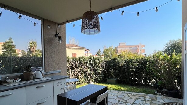 Une terrasse extérieure comprenant un espace cuisine, une table à manger et des chaises.