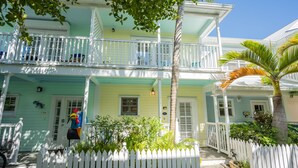 A two-story house with a white picket fence, a front porch, and a palm tree. - Conch Get Enough at The Truman Annex in Key West (Key West)