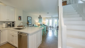 A modern kitchen with white cabinetry, a dishwasher, and a central island with seating. - Conch Get Enough at The Truman Annex in Key West (Key West)