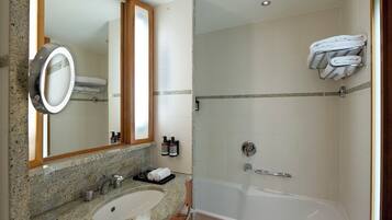 A modern bathroom with a granite countertop sink, a large mirror, a glass-enclosed shower, and a towel rack.