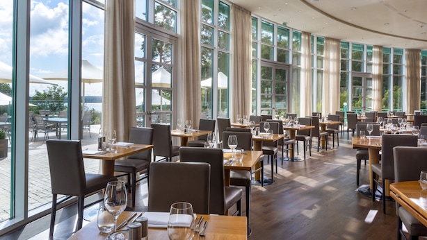 Un restaurante con amplios ventanales, mesas y sillas de madera.