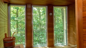 Una cabaña de madera con ventanas amplias que dan a un bosque.