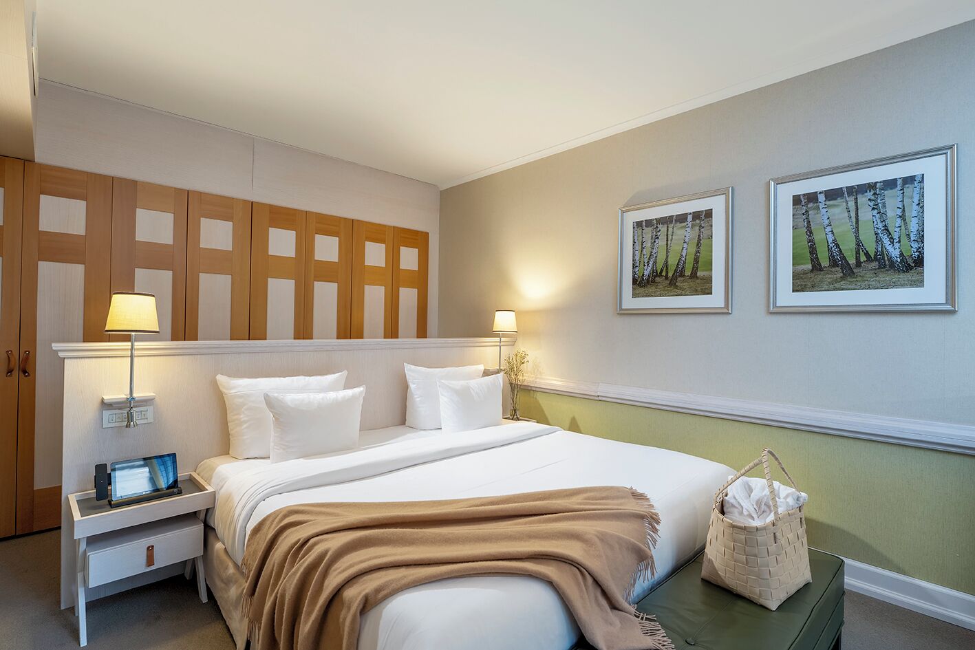 Een hotelkamer met een bed, nachtkastjes, een lamp en twee ingelijste foto's aan de muur.