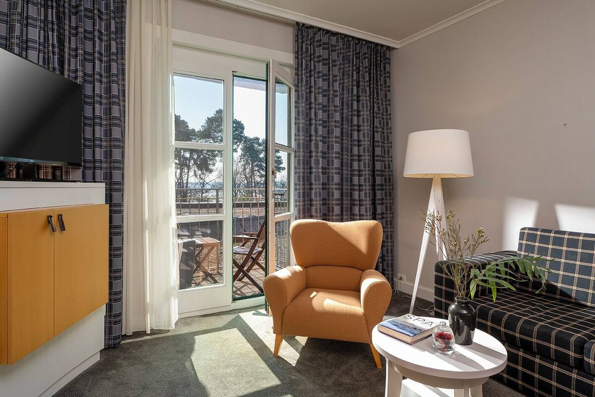 Una sala de estar moderna con un sofá, un sillón y un televisor sobre un mueble.