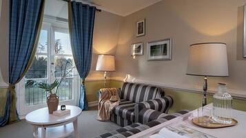 A cozy living room with a striped sofa, a small round table, and a window with curtains.