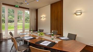 Een vergaderruimte met een lange tafel, stoelen en een schaal fruit.