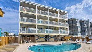 Um hotel com vários andares e área de piscina, incluindo piscina, espreguiçadeiras e um deck de madeira.