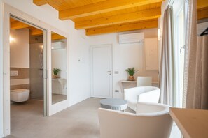 A modern bathroom with a glass-enclosed shower, a white toilet, and a small round table with a chair.