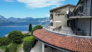 A hotel with a terrace, a view of the mountains, and a pool area.