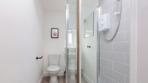 Et moderne badeværelse med glasbrusekabine, toilet og håndvask.