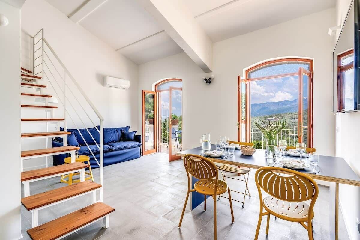Ein modernes Interieur mit einer Treppe, einem Essbereich mit Aussicht und einem blauen Sofa.