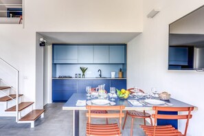 A modern kitchen with blue cabinets, a dining table set for four, and a staircase leading to an upper level.