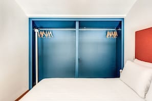 A bedroom with a bed, a blue wardrobe, and a red headboard.